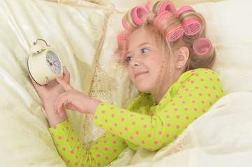 Happy cute little girl in hair curlers awaked