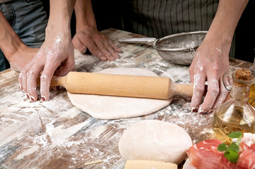 Woman with child preparing dough for homemade pizza. Light toning