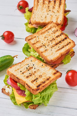 Fototapeta na wymiar Three sandwiches with ham, lettuce and fresh vegetables on a white background