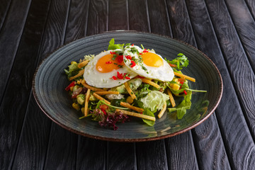 Fried eggs with avocado, salad leaves and crispy chips