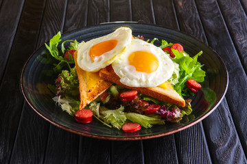 Fried eggs with toast, melted cheese and salad leaves