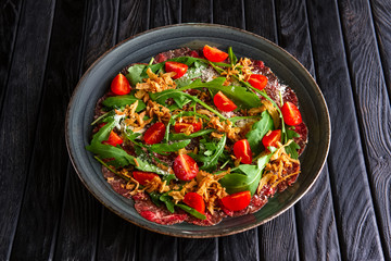 Beef carpaccio with tomato cherry, arugula and deep fried bacon