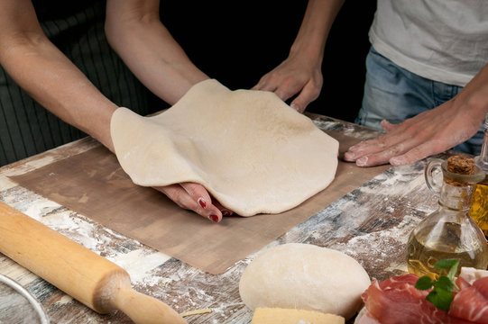 Women's hands rolling out the dough for homemade pizza