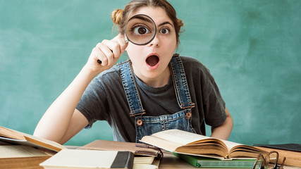 Shocked student looking through a magnifying glass - obrazy, fototapety, plakaty