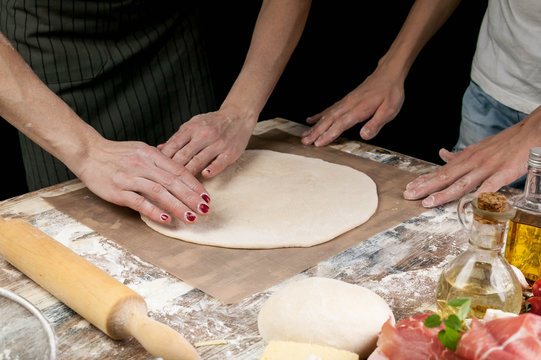 Women's hands rolling out the dough for homemade pizza