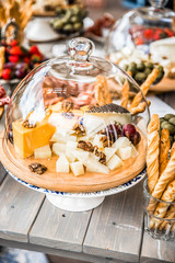 Different cheeses with walnuts and grapes under a glass bell jar
