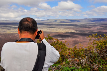 A photographer taking a photo of the Sierra Negra Volcano, Isabela Island, Galapagos, Ecuador