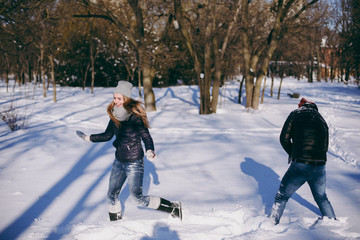 Fototapeta na wymiar Happy funny couple woman and man in warm clothes catching up with each other, walking in snowy park or forest outdoors. Winter fun, leisure on holidays. Love relationship people lifestyle concept.