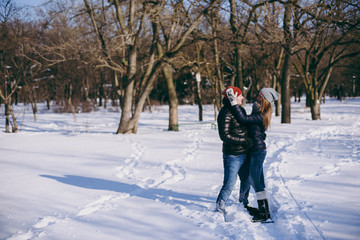 Fototapeta na wymiar Beautiful couple woman, man in winter warm clothes looking at each other, hugging walking in snowy park or forest outdoors. Winter fun, leisure on holidays. Love relationship people lifestyle concept.
