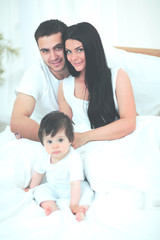 Obraz premium Cute little boy with parents on the bed