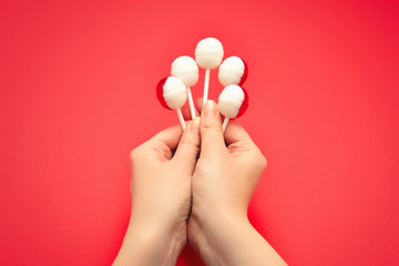 Lollipop in female hand on red background. Space for text or design.
