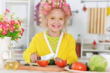 cute little girl with hair curlers cooking at kitchen