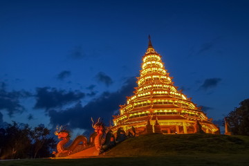 Fototapeta premium Wat Huay Pla Kang, beautiful golden pagoda chinest style decorate with lighting at night with cloudy sky background, chinese temple in Chiang Rai, Thailand.
