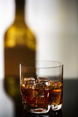 Gorgeous view of glass of alcohol drink with ice on shadow of bottle background. Beautiful backgrounds.