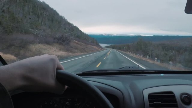 Driving POV on top of a mountains peak. The window view is larger mountains in the distance.