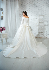 Rear view shot of bride wearing gorgeous luxurious wedding dress with long loop in the bright...
