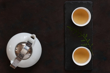 White porcelain Asian tea set with green tea Milk Oolong on black stone desk. Close up, top view.