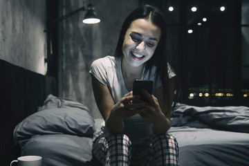 Portrait of female chatting, using smartphone at night. Dating app concept