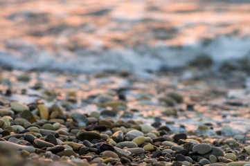 pebble stones on the sea beach, the rolling waves of the sea with foam