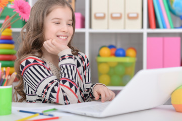 Portrait of happy little girl using modern laptop