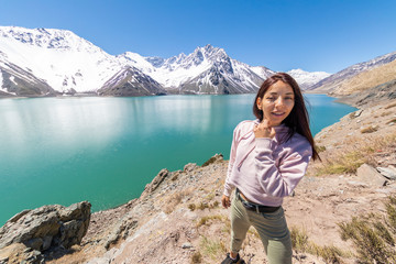 Girl looking at the amazing mountain views of the turquoise waters from the "Embalse del Yeso" (Cast Lake) close to Santiago de Chile city in Andes mountains. Snow mountains and water reflections