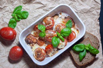 Closeup detail look on fresh vegetarian sliced and salted tomatoes ready to bake covered with cheese and fresh organic basil