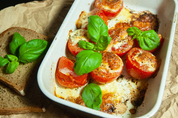 Closeup detail look on fresh vegetarian sliced and salted tomatoes ready to bake covered with cheese and fresh organic basil