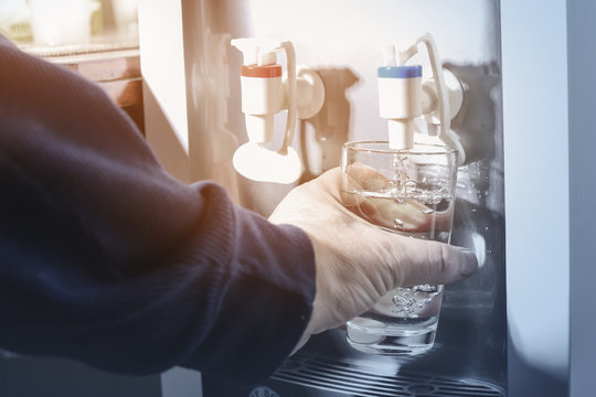 Male Hand Serving Water Of A Water Cooler