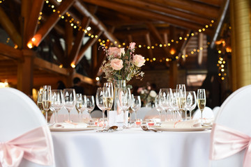 Wedding. Banquet. The chairs and round table for guests, served with cutlery, flowers and crockery and covered with a tablecloth.