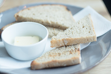 Some pieces of a white bread with butter on the grey plate.
