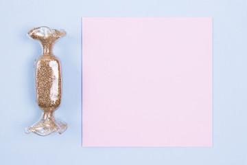 Pink blank card mockup and a toy in the shape of holidays candy on blue background. Flat lay.