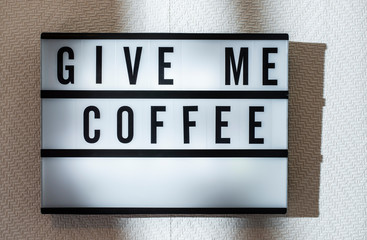 Message Give Me Coffee on illuminated board. Coffee drinking concept with text.