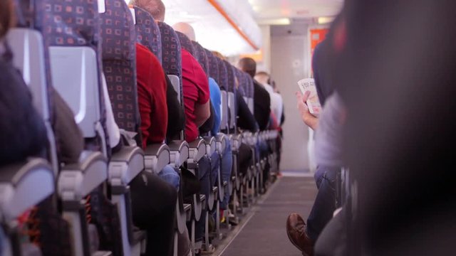 Passenger reading a newspaper on an airplane.