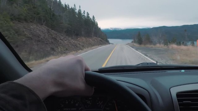 Driving POV on top of a mountains peak. The window view is larger mountains in the distance.