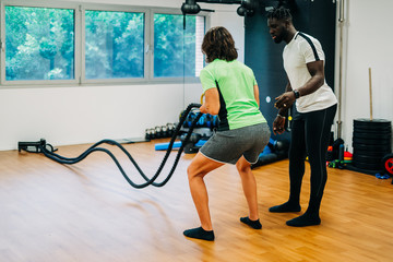 Man with battle rope in functional training fitness gym