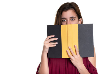 Pretty teenage girl hides her face behind a book