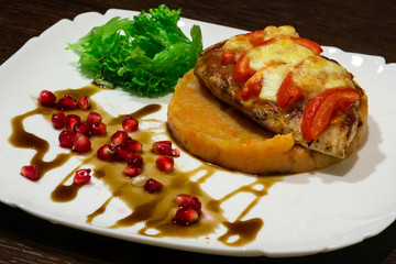  meat dish. Steak with mashed potatoes, greens, soy sauce and pomegranate seeds. In a plate on the table. Close-up