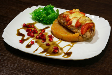  meat dish. Steak with mashed potatoes, greens, soy sauce and pomegranate seeds. In a plate on the table