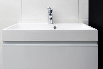 Modern interior of bathroom with white square sink and chrome faucet