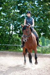 Young lady riding a horse at equestrian school. Training process