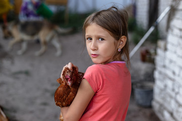 Little rural girl with chicken in her arms