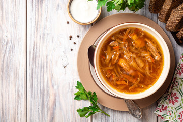 Traditional Russian sauerkraut soup Shchi in bowl on rustic wooden background. Top view. Copy space.