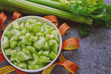 Sliced celery in a bowl and measuring tape. Concept of weight loss with celery.