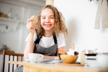Obraz na płótnie Canvas Young cute girl eating oat cookie and smiling. Family love and care concept.