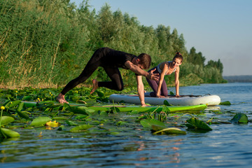 Sports couple doing exercise on river in summer