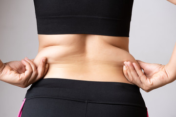 Fat woman hand holding excessive belly fat. Healthcare and woman diet lifestyle concept to reduce...