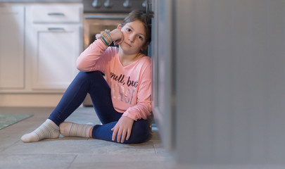 Young girl in a pink shirt sitting on the floor looking at the camera 