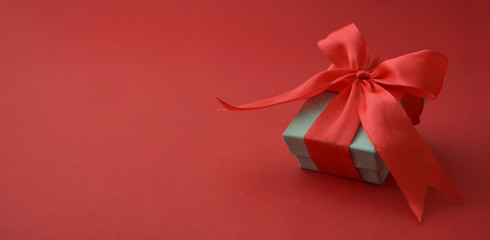 Close up gift box, birtday gift with red bow on red background. Love, Valentine's Day, Mother's Day. Banner.