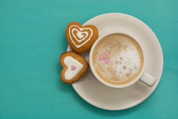Cup of coffee or latte and heart shaped cookies, biscuits. Blue background, copy space. Caffeine drink lovers. Morning coffee with milk.