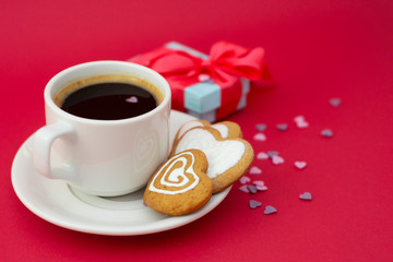 Love, Valentine's Day. Cup of coffee and heart shaped cookies, biscuits. Top view. Red background with gift boxes.